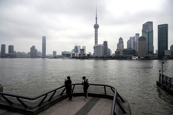 Pedestrians stand on the Bund against the backdrop of the Shanghai skyline. Photo: Bloomberg