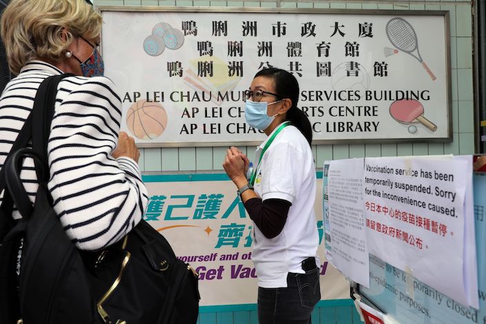 A staff member assists a person outside a closed community vaccination center administering the BioNTech Covid-19 vaccine imported by Fosun Pharma in Hong Kong