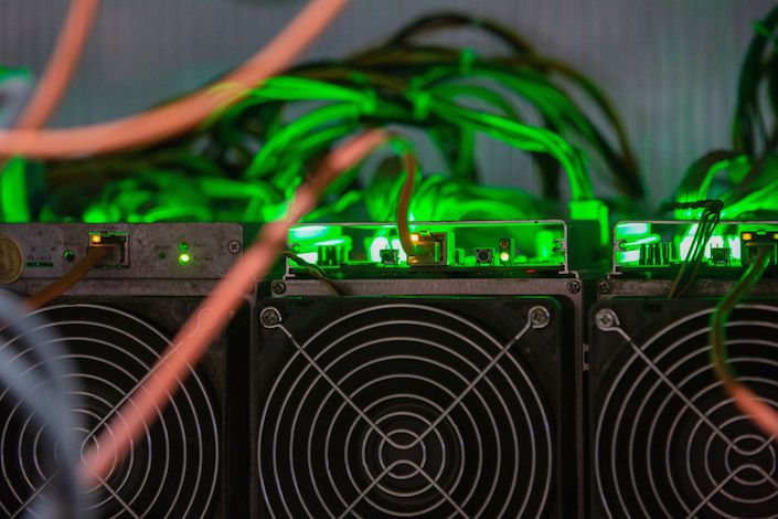 Mining devices and power units mounted in racks at the CryptoUniverse cryptocurrency mining farm in Nadvoitsy