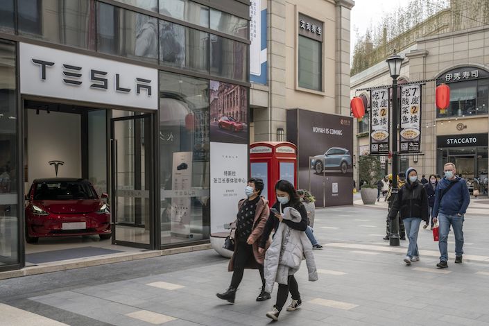 Shoppers walk past the Tesla Inc. showroom at the Chamtime Plaza in Shanghai