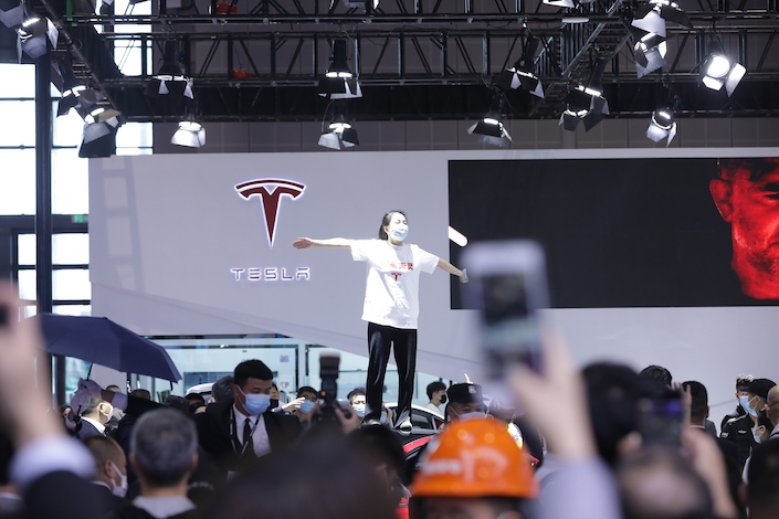 A woman climbed onto a red Model 3 at Tesla’s booth in the Shanghai Auto Show Monday, wearing a T-shirt reading “Brakes Lost Control” in Chinese.