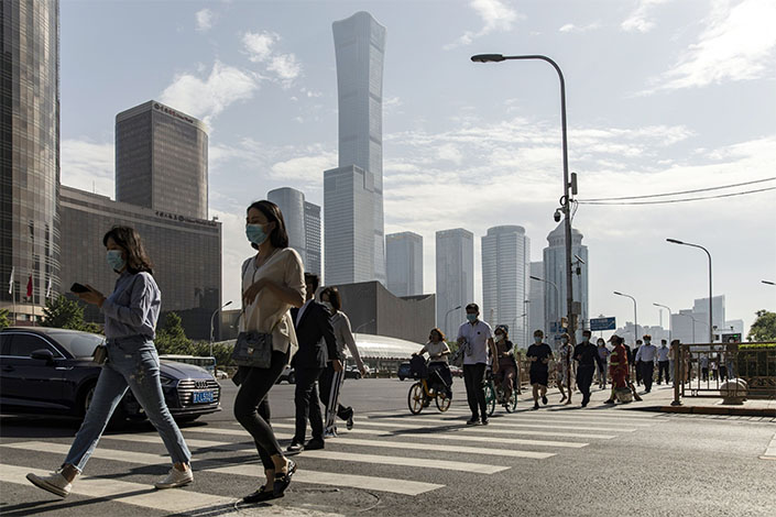 Pedestrians wearing protective masks walk across a road in the central business district in Beijing on May 27.  Photo: Bloomberg