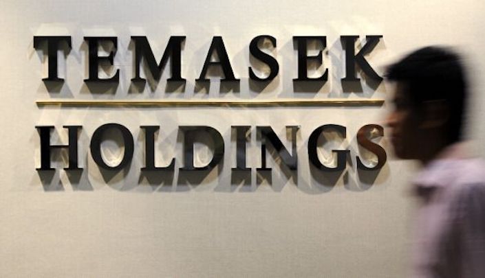 A Temasek Holdings Pte employee walks past the company's signage in their office in Singapore