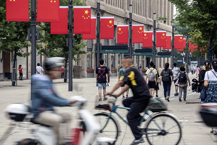 Pedestrians walk past Chinese flags hanging from lamp posts in Shanghai on July 1. Photo: Bloomberg