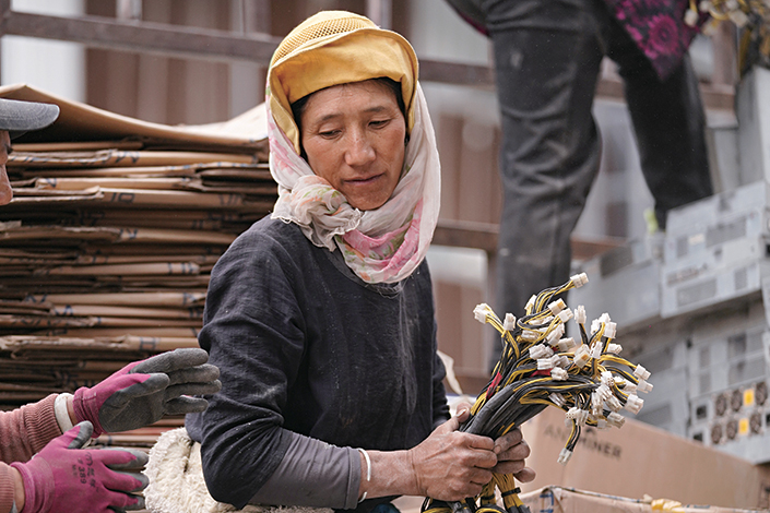 An ethnic Tibetan woman in Sichuan province’s Heishui county carries components of cryptocurrency mining machines that were sent from the Xinjiang Uyghur autonomous region on May 2. Photo: Ding Gang/Caixin