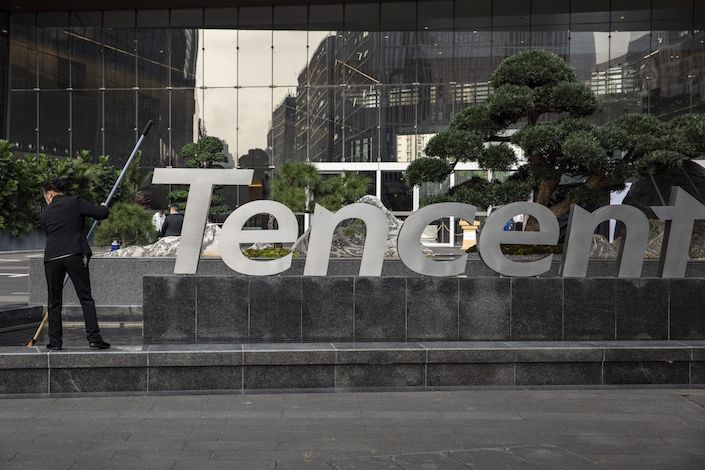 A worker cleans a water features next to a Tencent Holding Ltd. logo at the company's headquarters in Shenzhen