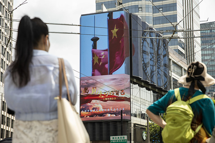 A public screen displays an image of Chinese flags in Shanghai