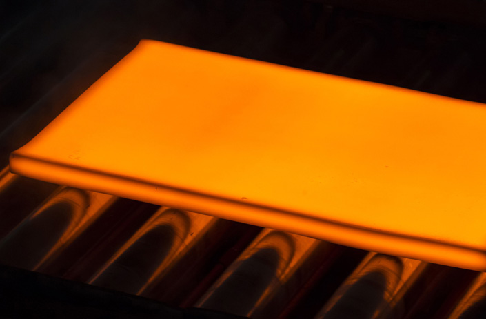 A hot steel slab moves along a conveyor of a plate mill at the Nippon Steel & Sumitomo Metal Corp. plant in Kashima