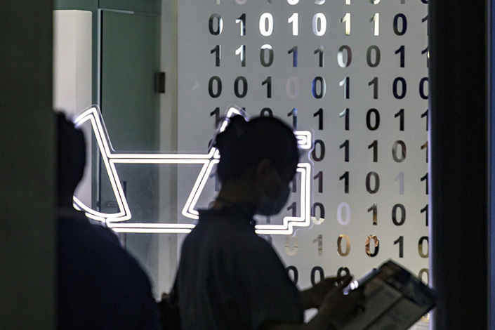 An attendee walks past a wall with binary codes at the World Artificial Intelligence Conference (WAIC) in Shanghai