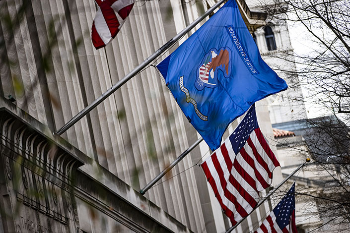 American and U.S. Department of Justice (DOJ) flags fly outside DOJ headquarters in Washington