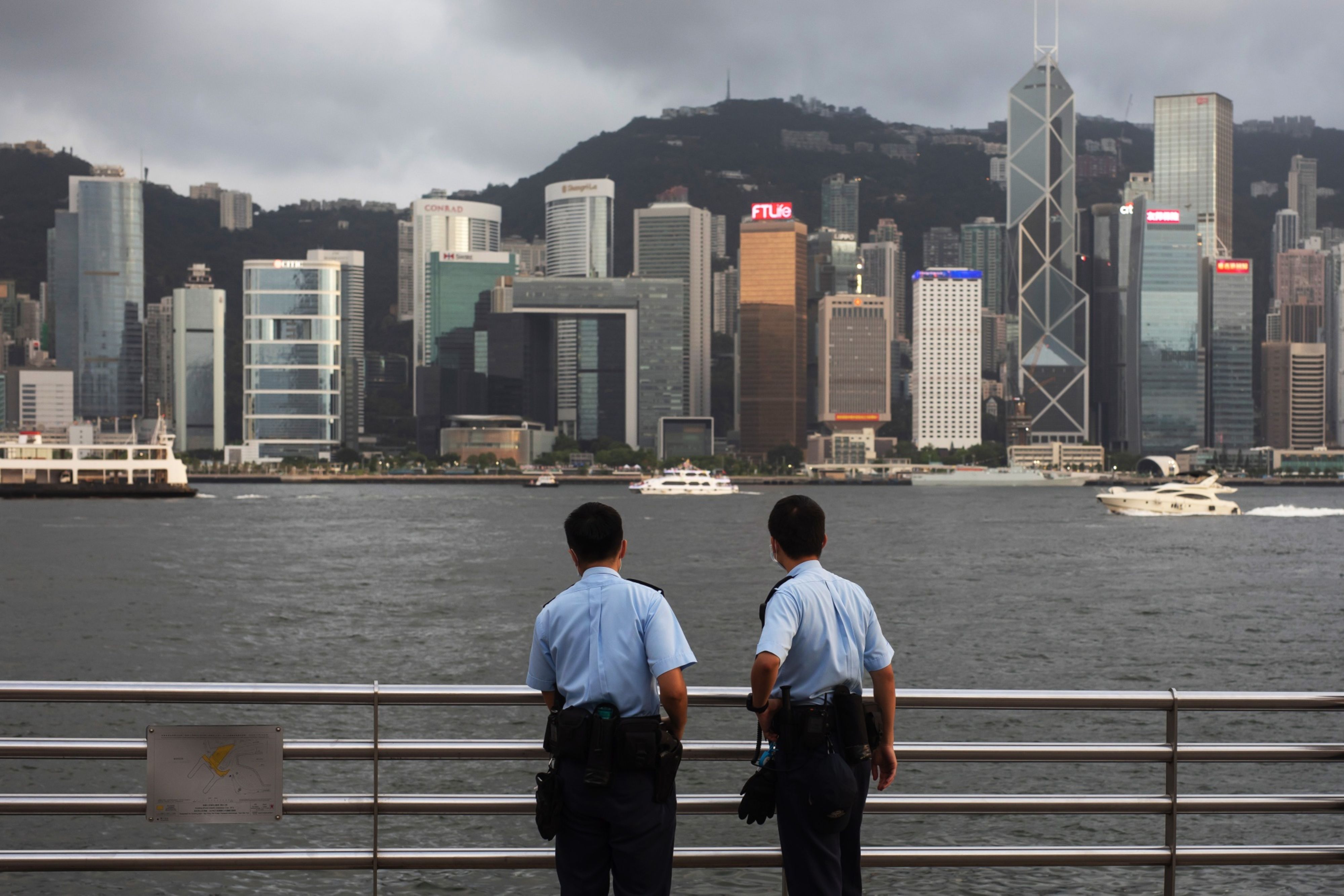 Police officers stand guard in front of the skyline at Tsim Sha Tsui in Hong Kong