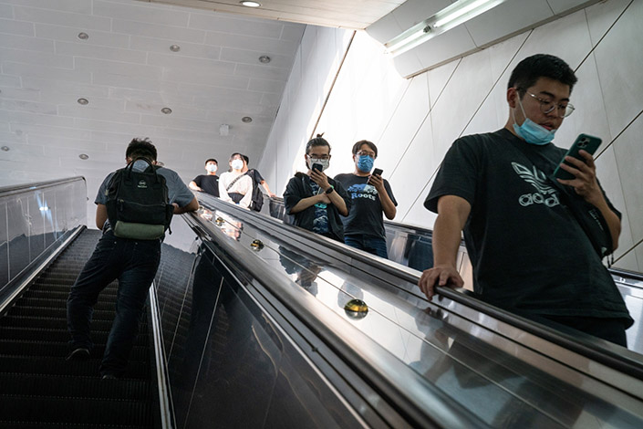 Visitors use their smartphones as they ride on an escalator in Beijing on July 16. Photo: Bloomberg