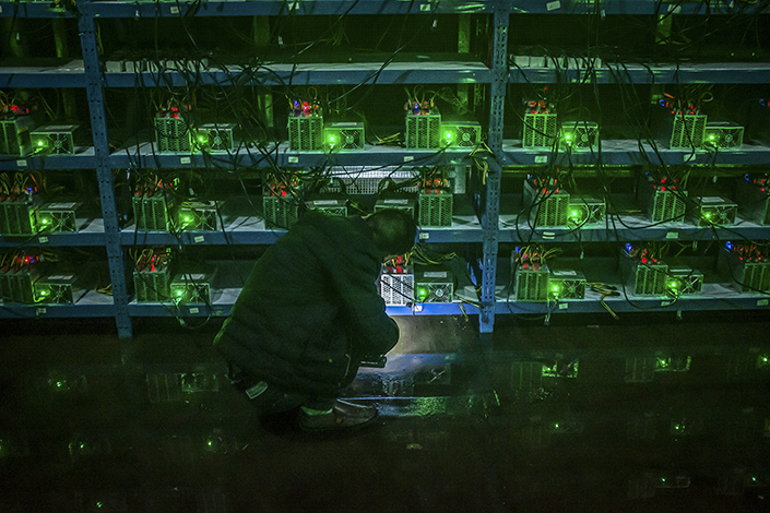 A worker inspects a Bitcoin mining machine in a mining pool in Ngawa Tibetan and Qiang Autonomous Prefecture, Southwest China's Sichuan province. Photo: VCG