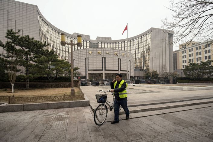 A man pushes a bike past the People's Bank of China (PBOC) building in Beijing on March 4.  Photo: Bloomberg
