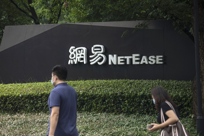 Pedestrians wearing protective masks walk past signage at the NetEase campus in Hangzhou on June 10, 2020. Photo: Bloomberg
