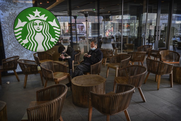 Chinese men wear protective masks as they sit in a nearly empty Starbucks in Sanlitun on March 10, 2020 in Beijing. Photo: Bloomberg