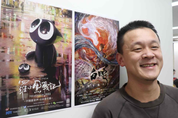 Facewhite founder Dong Zhiling stands with posters for the animated films “The Legend of Hei” and “White Snake.” Photo: Shuhei Yamada/Nikkei Asia
