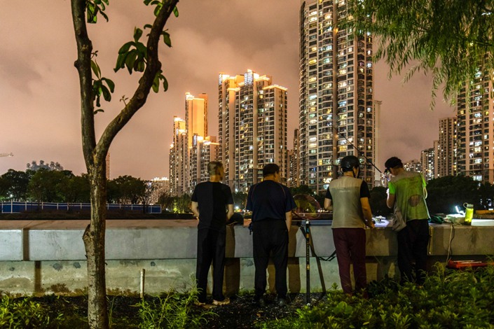 Men fish near a large residential compound in Shanghai on Sept. 29. Photo: Bloomberg
