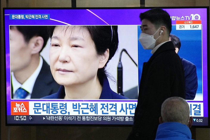 A man passes by a TV screen showing a file image of former South Korean President Park Geun-hye during a news program at the Seoul Railway Station in Seoul, South Korea, Friday, Dec. 24, 2021. The South Korean government said Friday it will grant a special pardon to Park. Photo: VCG