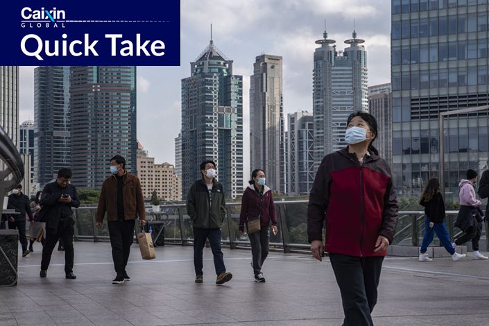 Pedestrians wearing protective masks walk through the Lujiazui financial district in Shanghai