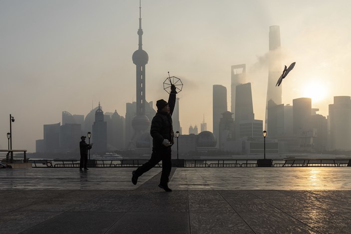 A pedestrian flies a kite against the backdrop of the Lujiazui financial district at sunrise in Shanghai on Jan. 4. Photo: Bloomberg