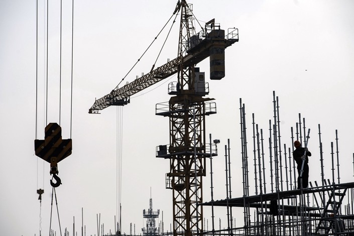 A worker stands next to a crane at a construction site for a residential development on the outskirts of Shanghai. Photo:Bloomberg