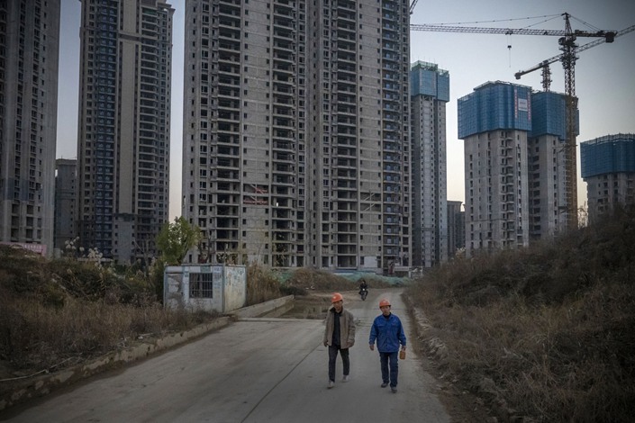 Workers walk near unfinished apartment buildings at the construction site of a China Evergrande Group development in Wuhan on Dec. 22, 2021. Photo: Bloomberg