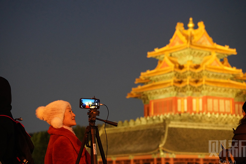 2022年2月15日，北京， 18时过后，护城河北岸和西岸的射灯准时启动，灯光照亮角楼，游客在角楼前自拍。