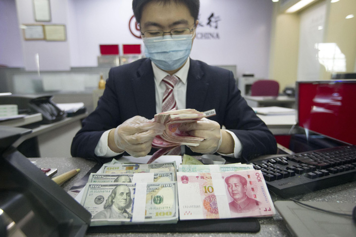 A bank employee counts 100 yuan notes in East China’s Jiangsu province in March 2021. Photo: VCG