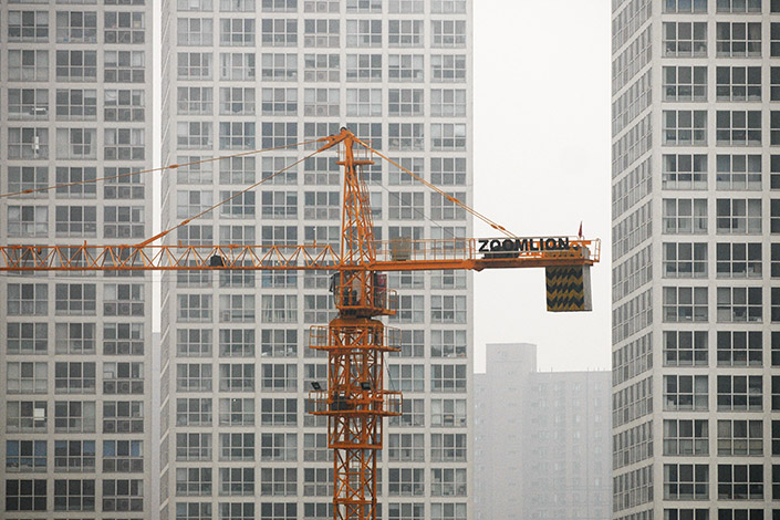 A crane stands in front of residential buildings in Beijing. Photo: VCG