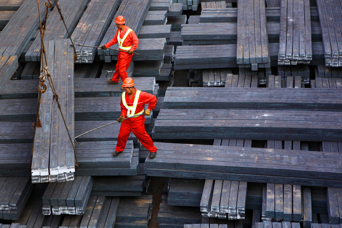 Two workers load crude steel in East China’s Jiangsu province. Photo: VCG