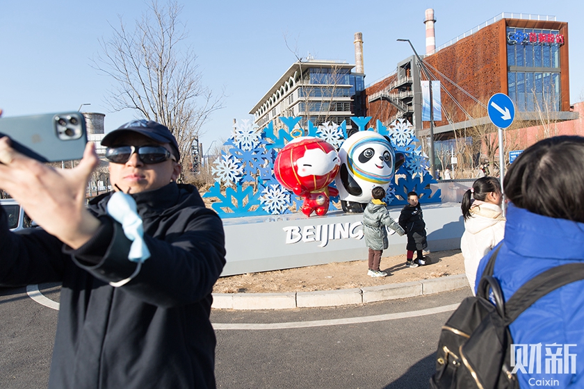 北京首钢园南门处，游客在冬奥吉祥物雕塑前拍照。
