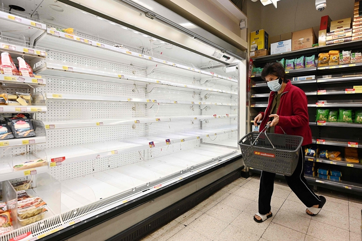 A woman walks past a empty shelves at a supermarket Tuesday in Hong Kong amid the city's Covid-19 outbreak. Photo: VCG