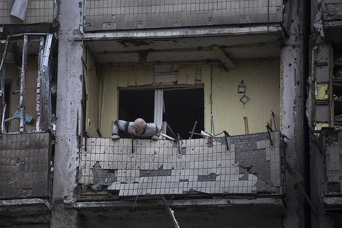 A man checks the façade of a bomb-damaged building in Kyiv on Friday.