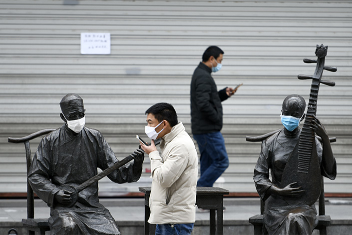 A man passes by statues donning masks at a street in Jiaxing, East China’s Zhejiang province, in February 2020. Photo: VCG