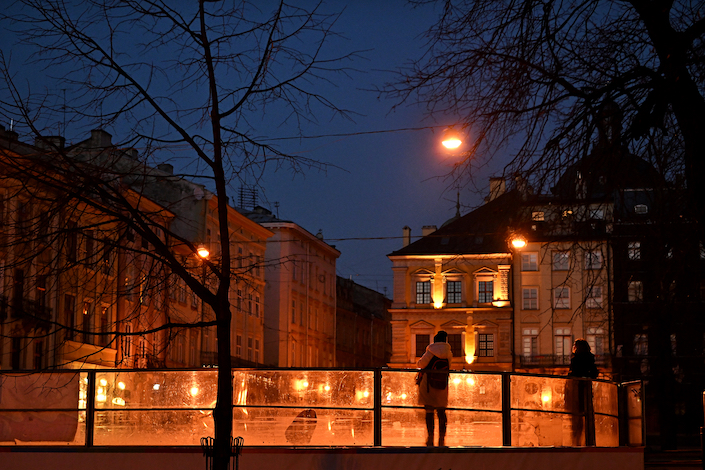 People watch as children play in an ice skating rink at Central Square in Lviv, Ukraine, March 14