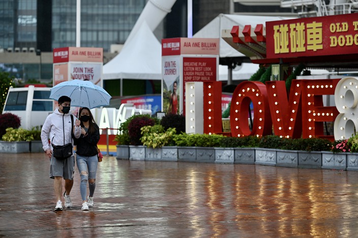 A couple walk together under an umbrella on March 23 in Hong Kong. Photo: VCG