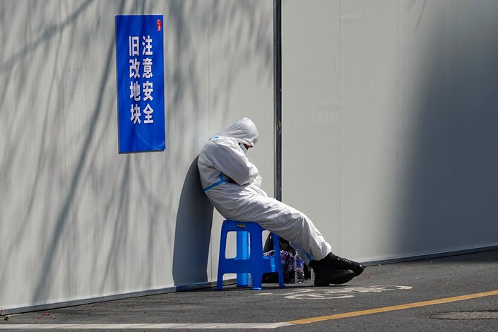 Medical workers rest against a wall in Shanghai on March 23, 2022. Photo: VCG