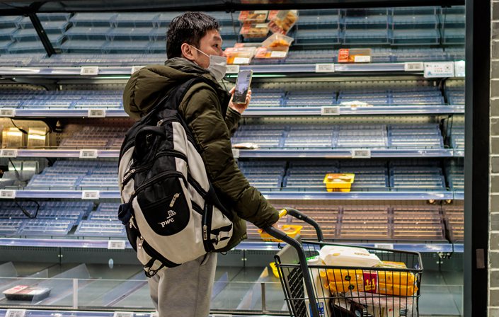 A costomer buys food in a half-empty grocery store in Shanghai on March 25, 2022. Photo: The Paper