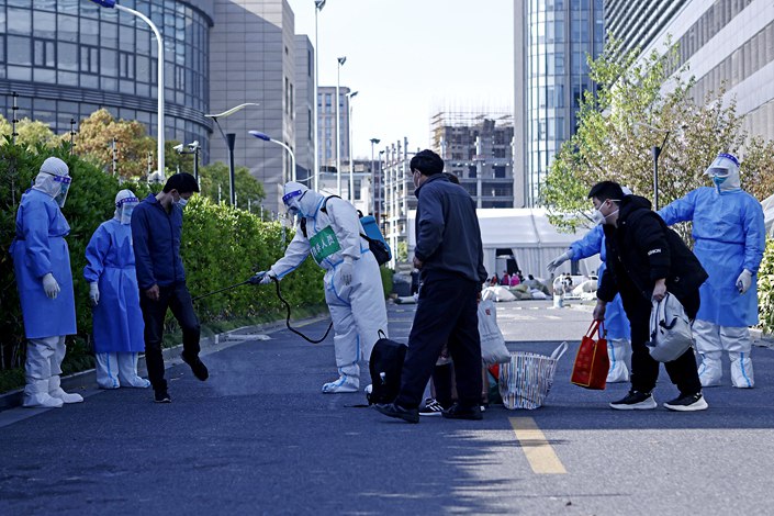 Staff disinfect the belongings Saturday of the first group of recovered patients to be released from the makeshift hospital set up at the Shanghai International Procurement Convention and Exhibition Center. Photo: VCG