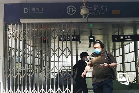2022年5月4日下午3时许，北京市青年路地铁站出入口封闭，乘客走出地铁站，工作人员拉起铁门。据“北京地铁”官方微博消息，根据疫情防控需要，自2022年5月4日15时起至另有通知止，部分地铁车站采取出入口封闭措施停止进出站，其中涉及的换乘站可站内换乘。图：财新 张芮雪