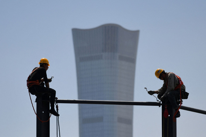 Two workers build a steel structure at a construction site in Beijing in May 2021. Photo: VCG