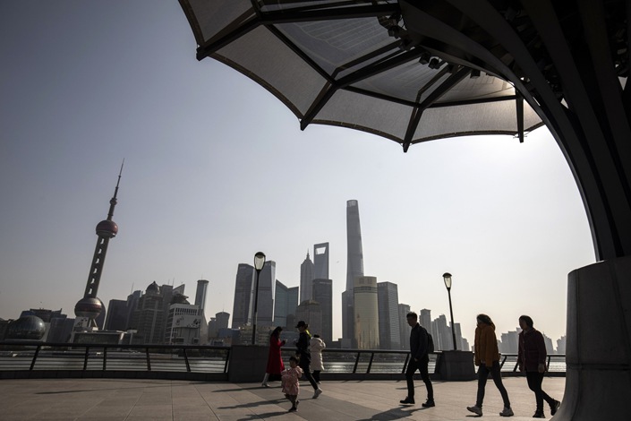 Pedestrians along the Bund in front of buildings in the Lujiazui Financial District across the Huangpu River in Shanghai, China, on Friday, Feb. 27, 2022. Photo: Bloomberg