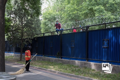 5月22日下午15时许，北京理工大学中关村校区西侧，工人正在校园围栏上加装防跨越铁丝网。据5月21日北京海淀官方发布，自5月21日12时至5月28日12时（暂定），海淀区全域实行提级管控措施。北京理工大学中关村校区北门和东南门的保安均表示，在校学生原则上不可出校。图：财新 丁可（实习）