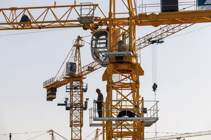 A worker stands on a crane at the Sunac Resort project construction site on Feb. 25. Photo: Bloomberg