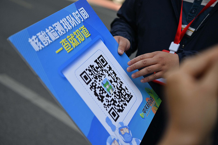 A worker holds up a QR code that allows people to check the time it will take to queue for nucleic acid testing in Beijing on May 17. Photo: VCG