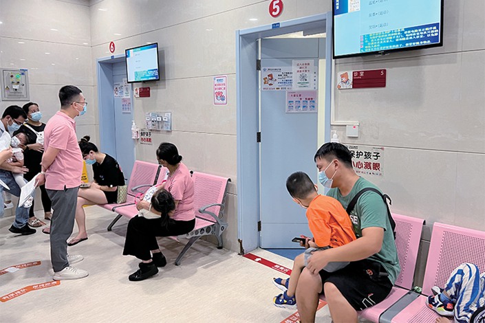 Parents wait with their children outside the fever clinic of Guangzhou Women and Children's Medical Center in Guangzhou, South China's Guangdong province, on June 27. Photo: Qi Zhanning/Caixin