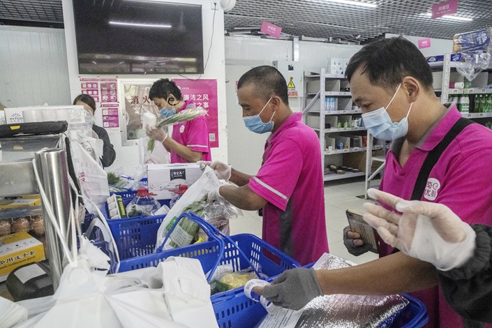 Employees package groceries for delivery at a Missfresh warehouse, operated by Beijing Missfresh Ecommerce Co., in Beijing. Photo: VCG