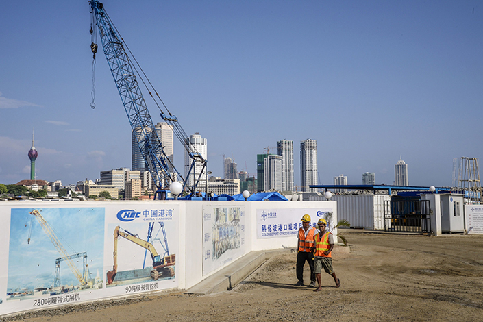Workers walk past hoardings for the Colombo Port City, developed by China Harbour Engineering Co., a unit of China Communications Construction Co., in Colombo, Sri Lanka, on March 30, 2018. Photo: Bloomberg