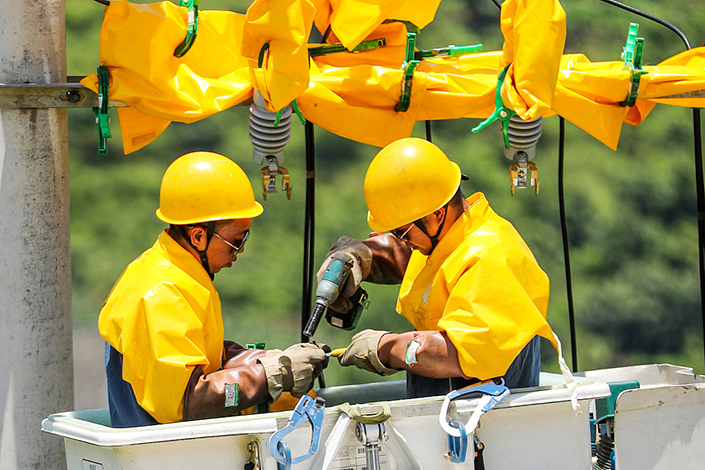 Maintenance staff work on power lines in Bijie, Guizhou province, in July 2021.